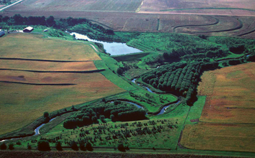 Aerial photo of farm fields, a body of water, and trees